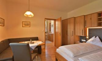 A cozy room with two beds and a sitting area. The wooden furniture and warm colors create an inviting atmosphere.