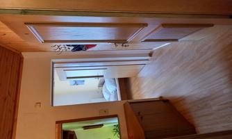 A beautiful hallway with wood veneer and a mirror. In the background, a bedroom is visible.
