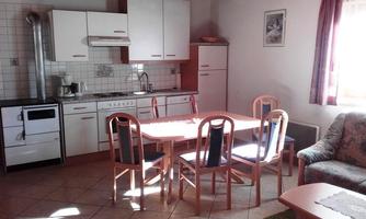 A cozy kitchen with a dining area and a sofa. The room is bright and inviting, with modern furniture and a window that lets in daylight.