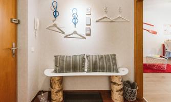 A cozyentrance area with a bench and striped cushions. 

Hangers and decorative elements are hanging on the wall.