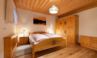 A cozy bedroom with a wooden ceiling and classic furniture. The room is bright and inviting, with a piece of artwork on the wall.