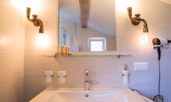 An elegant bathroom with a modern sink and large mirrors. On the wall, there are stylish lights and practical holders for toiletries.