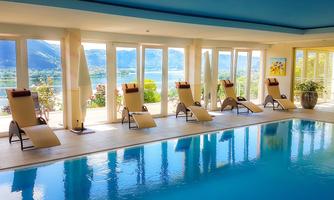 An elegant pool area with loungers and large windows that offer a stunning view of the landscape. The water reflects the surroundings and creates a relaxing atmosphere.