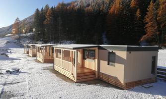 Modern cabins in a snowy landscape. The surroundings are surrounded by forest and mountains.