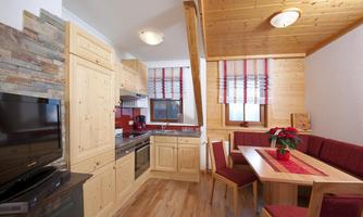 A cozy kitchen with wooden furniture and a dining area. Large windows provide bright light and an inviting atmosphere.