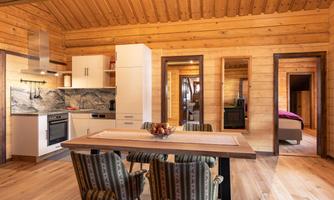 A modern, bright kitchen in a wooden house with a dining area. The decor is simple and welcoming, ideal for cozy family dinners.