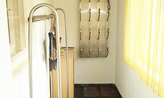 A bright interior with a pegboard on the wall. The floor is covered with a black mat and there is a window with yellow curtains.