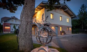 A modern house with a beautiful garden and a staircase. In the foreground, there is a decorative globe sculpture.
