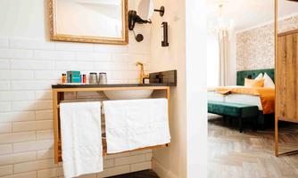 A modern bathroom with a stylish sink and elegant fixtures. In the background, a cozy bedroom is visible.