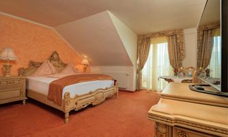 An elegant bedroom with a large bed and luxurious furnishings. Large windows provide ample light and a cozy atmosphere.