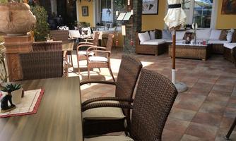 A cozy interior with rattan furniture and a large table. There is a relaxed atmosphere with beautiful decoration and plenty of natural light.