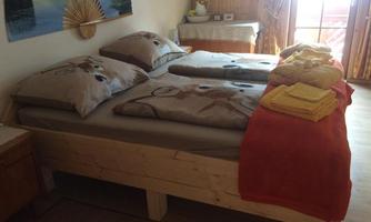 A cozy bedroom with a double bed and decorative cushions. Stacked towels in yellow and orange are lying on the bed.