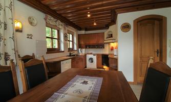A cozy kitchen with a wooden ceiling and a large dining table. The modern appliances are well integrated and there are large windows that let in plenty of light.