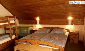 A cozy bedroom with wooden furniture. There is a double bed and a bunk bed, as well as a table and a crib.