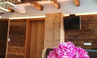 A bright interior with wood decor and modern elements. On the table, there is a vase with pink flowers.