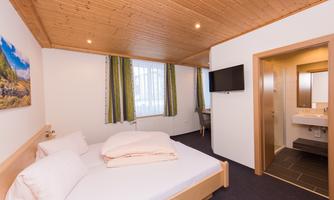 A modern room with a double bed and bright walls. A television and a bathroom are also available.