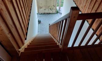 A wooden staircase leads down into a courtyard. The area is surrounded by white walls and a wooden fence.