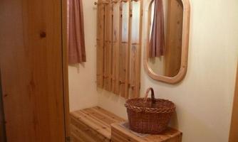 A cozy hallway with wooden furniture and a large mirror. Towels hang on the wall and a basket sits on a chest.