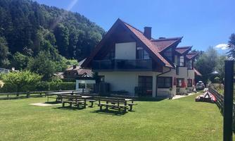 A beautiful house with a large garden and outdoor tables. Surrounded by trees and a picturesque landscape.