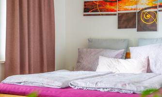 Large bed with soft pillows and warm colors, above it a modern picture and a mood lamp. Here, a day with the family comes to a relaxed end.