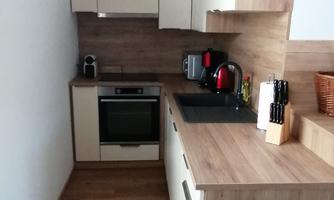A modern kitchen with bright cabinets and wooden surfaces. The room is well organized with a stove, a sink, and kitchen utensils.