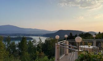 A tranquil view with mountains and a lake in the background. The scene is illuminated by the evening twilight.