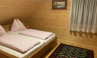 A cozy room with a double bed and wood-paneled walls. A carpet and a window with a curtain complement the inviting atmosphere.