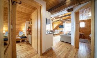 A cozy apartment with wood paneling and warm light. The open space features an inviting atmosphere with a living area and a dining space.