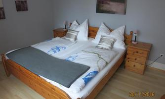 A cozy bedroom with a double bed and two nightstands. The bedding is simple, and the room has a bright, inviting look.