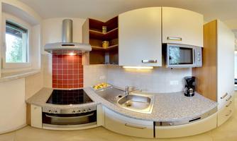 A modern kitchen with a cooktop, a sink, and a refrigerator. The walls are light, and there are some shelves for kitchen utensils.