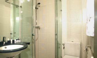 A modern bathroom with a shower, sink, and toilet. Bright tiles and a clear glass shower create a clean atmosphere.