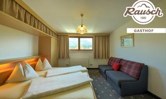 A cozy room with two beds and a sofa. Large windows offer a view of the mountains.