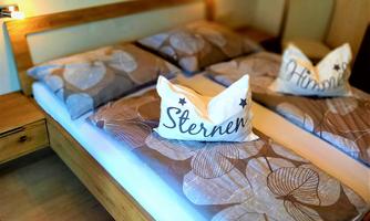 A cozy bedroom with a double bed and decorative pillows. The furnishings are made of wood and create a warm atmosphere.