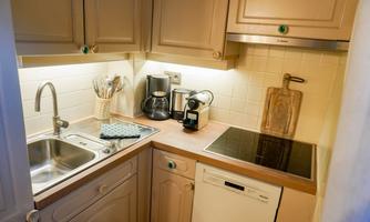 A modern kitchen with bright cabinets and a stylish countertop. On the countertop, there is a coffee machine, a toaster, and a cutting board.