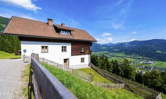 A beautiful house in a rural setting with a fantastic view of the mountains and the valley. The sky is clear and blue, perfect for a relaxing day.