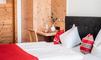 A cozy bedroom with a large bed and red accents. The wood style and the decor create an inviting atmosphere.