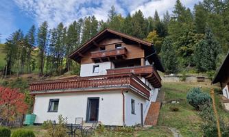 A charming house in the mountains with a wooden balcony and a large garden. Surrounded by trees and beautiful scenery.
