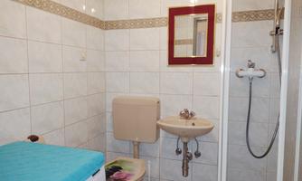 A small bathroom with bright tiles. It contains a toilet, a sink, and a shower.