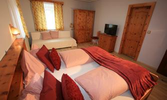 A cozy bedroom with two beds, comfortable pillows, and a bright, inviting atmosphere. There is also a television and a small seating area.