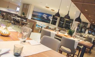A modern restaurant with elegant tables and chairs. Warm light and an inviting atmosphere create a cozy ambiance.