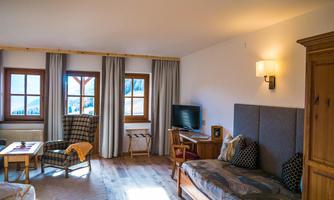 A cozy room with modern furniture and large windows. The view of the mountains creates an inviting atmosphere.