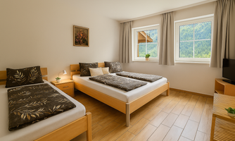 A modern room with two single beds and windows that overlook a picturesque landscape. The room is brightly and cheerfully furnished.
