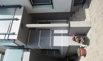 A modern entrance area with a simple staircase. Colorful flowers in pots give the surroundings an inviting accent.