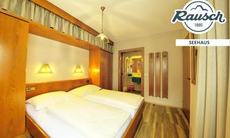 A cozy bedroom with two single beds and wooden shelves. The walls are painted in light colors, and there is soft lighting.