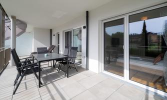 A modern terrace with a table and chairs. The space is bright and provides access to an indoor area.