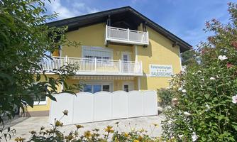 A yellow-painted holiday home with balconies and a garden full of flowers. The accommodation is designed to be friendly and welcoming.