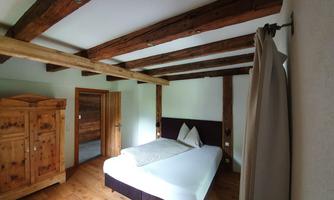 A cozy bedroom with wooden beams and a large bed. The room is simply furnished and radiates a warm atmosphere.