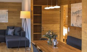 A cozy living space with wood paneling and modern furnishings. There is a dining room with a large table and a couch in the corner.