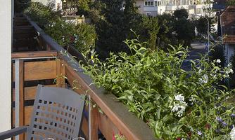 A beautiful balcony with a view of the mountains and the village. On the table are a bottle of rosé and two glasses.