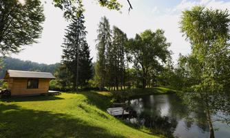 A quiet garden with a small wooden house and a pond.  
Surrounded by trees and green grass, it is a lovely place for relaxation.